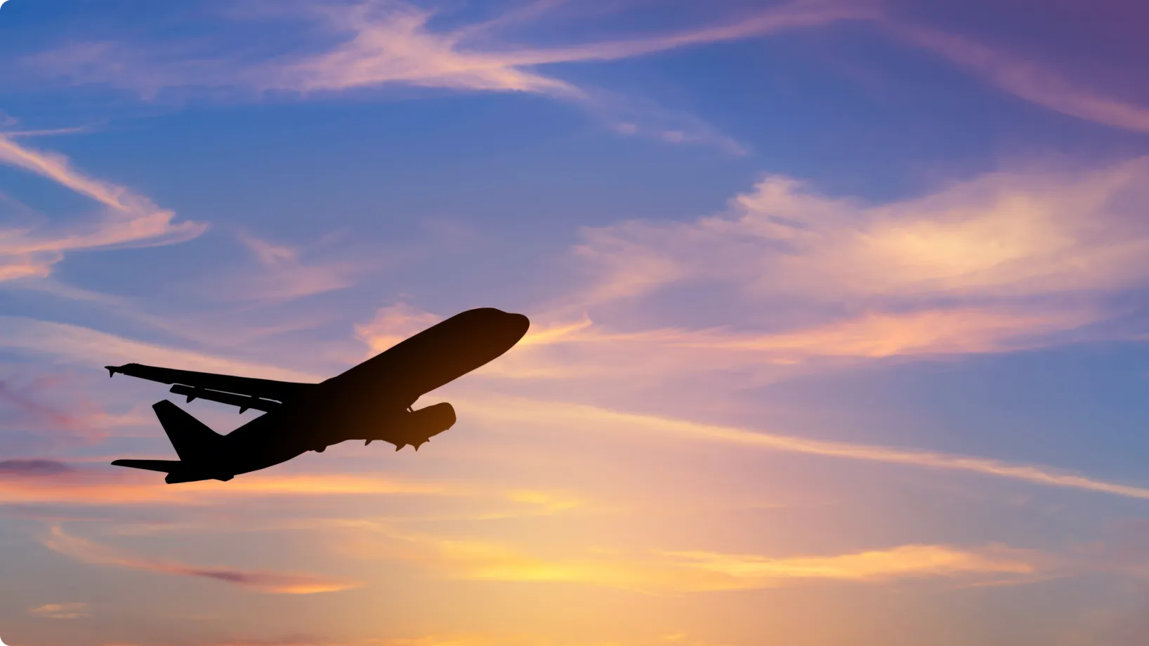 A passenger jet ascends through a sunset sky, its dark silhouette contrasted against purple, pink and orange clouds near the horizon.